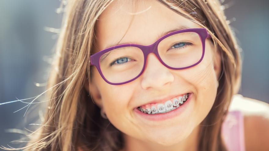 Lächelndes Mädchen mit lila Brille und Zahnspange