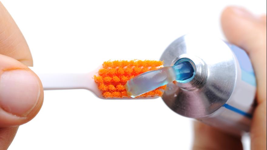 Zahnpasta wird auf Zahnbürste gedrückt