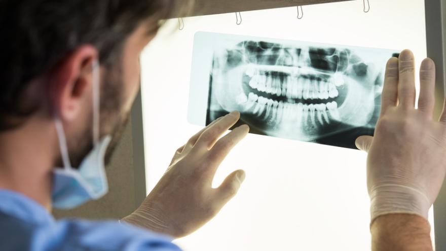 Zahnarzt schaut sich ein Röntgenbild vom einem Gebiss an
