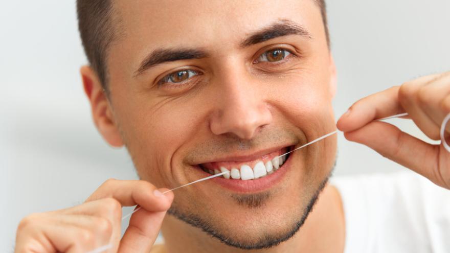 Mann reinigt seine Zähne mit Zahnseide