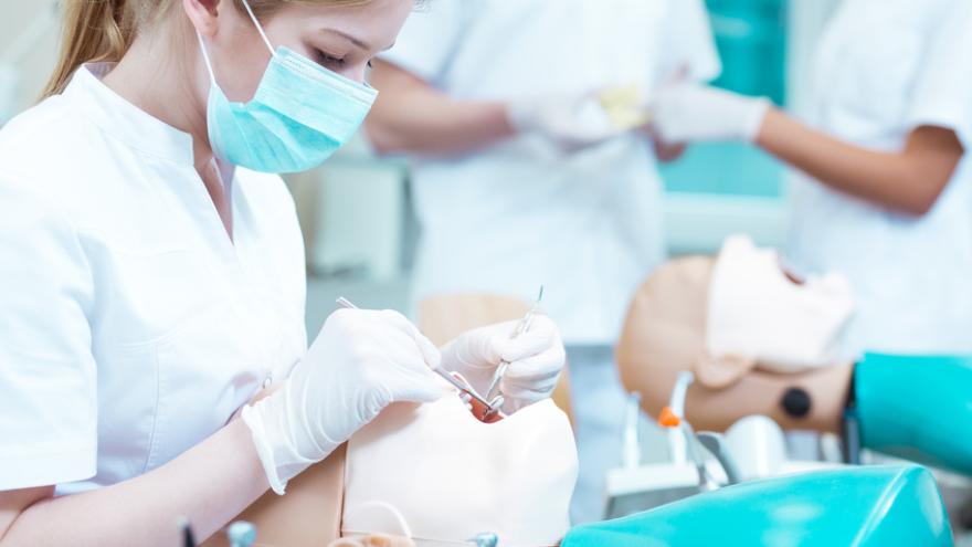 Ausbildung von Zahnärzten: Studenten der Zahnmedizin nehmen eine Zahn-Behandlung vor an einer Dummy Puppe